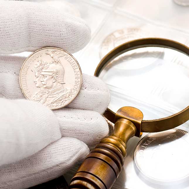 Close examination of a coin using gloves and a magnifying glass